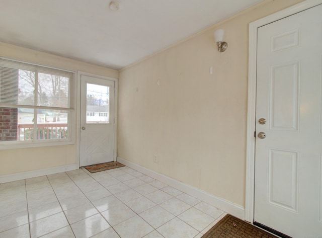 interior space with light tile patterned floors, crown molding, and baseboards