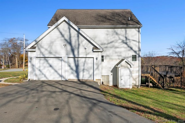 view of side of property with aphalt driveway, a lawn, and stairs