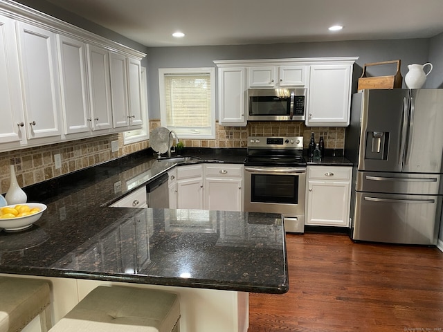 kitchen featuring stainless steel appliances, a sink, dark wood finished floors, and white cabinets