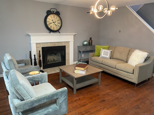 living room featuring a notable chandelier, a tiled fireplace, and wood finished floors