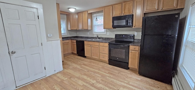 kitchen with dark countertops, a baseboard radiator, light wood-style flooring, black appliances, and a sink