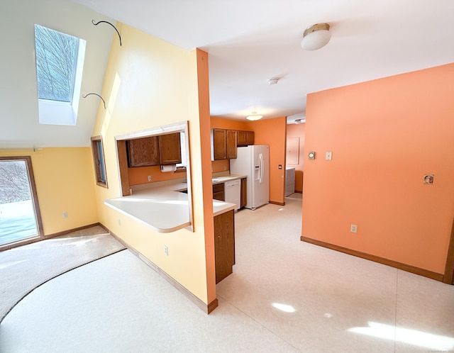 kitchen with light carpet, white appliances, a peninsula, light countertops, and baseboards