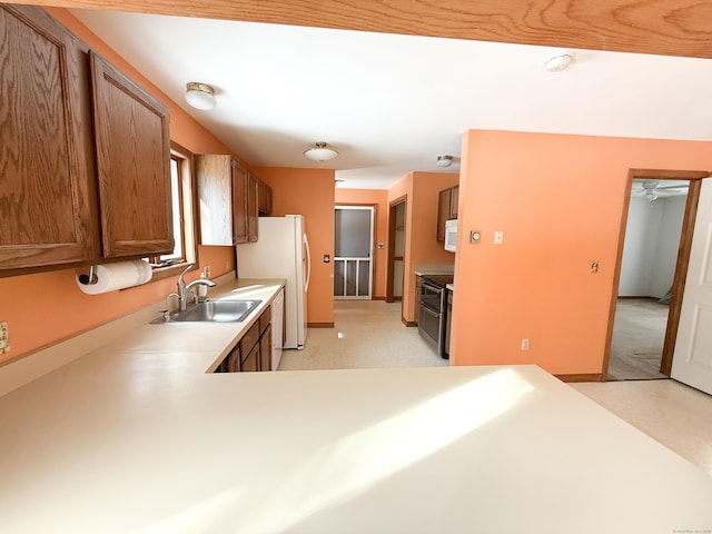 kitchen featuring baseboards, light countertops, brown cabinetry, white appliances, and a sink