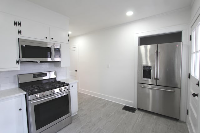 kitchen with baseboards, white cabinets, decorative backsplash, ornamental molding, and stainless steel appliances