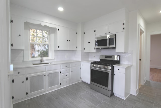 kitchen featuring stainless steel appliances, a sink, light countertops, and white cabinets