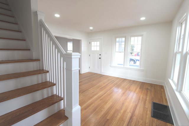 foyer entrance with light wood-style flooring, a healthy amount of sunlight, visible vents, and stairway