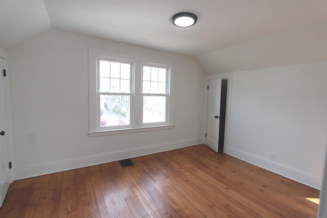 additional living space with lofted ceiling, visible vents, baseboards, and hardwood / wood-style flooring