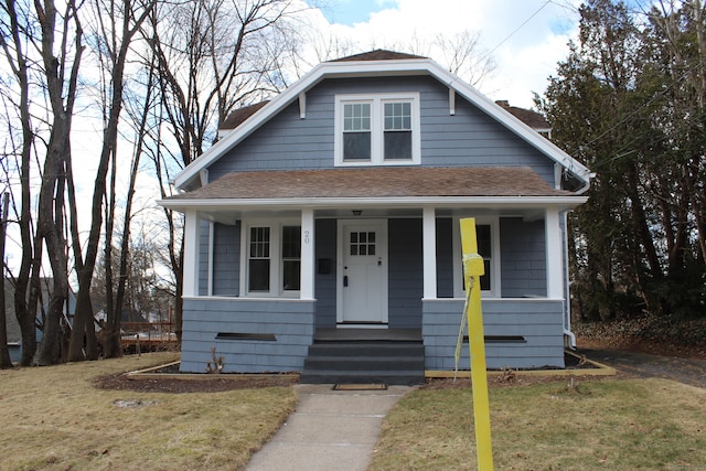 bungalow-style house featuring a porch, a front yard, and a shingled roof