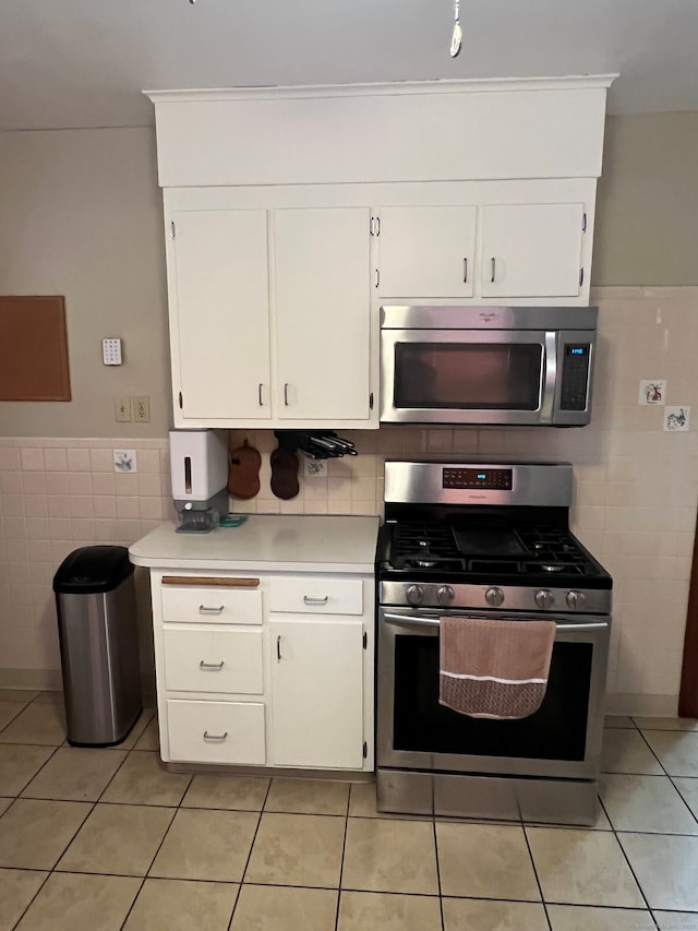 kitchen featuring appliances with stainless steel finishes, white cabinets, light countertops, and tile walls