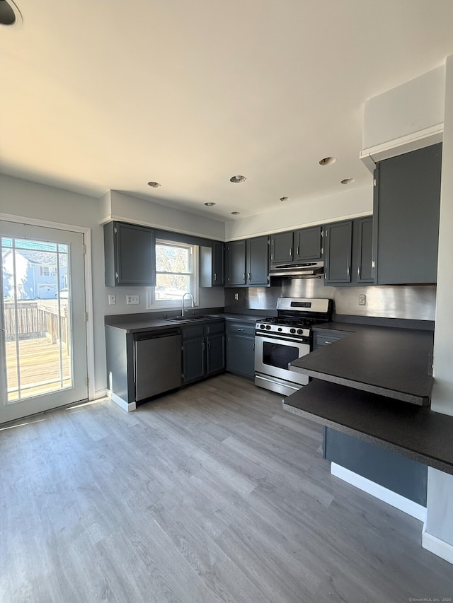 kitchen featuring dark countertops, light wood-style flooring, a sink, gas range, and dishwashing machine