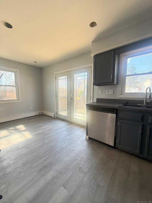 kitchen with dishwashing machine, wood finished floors, a sink, french doors, and dark countertops