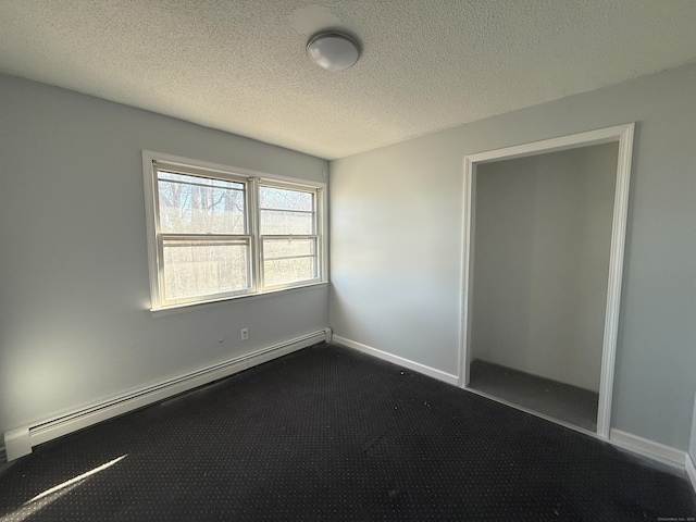 unfurnished bedroom featuring a textured ceiling, dark carpet, a baseboard radiator, and baseboards