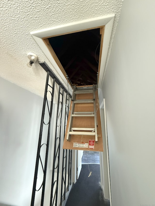 staircase with a textured ceiling and carpet floors