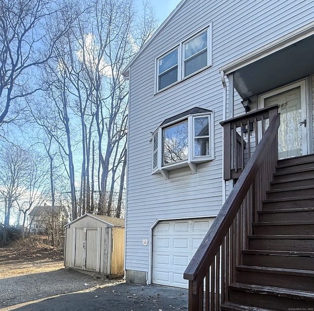 exterior space featuring a garage, a storage unit, aphalt driveway, and an outdoor structure