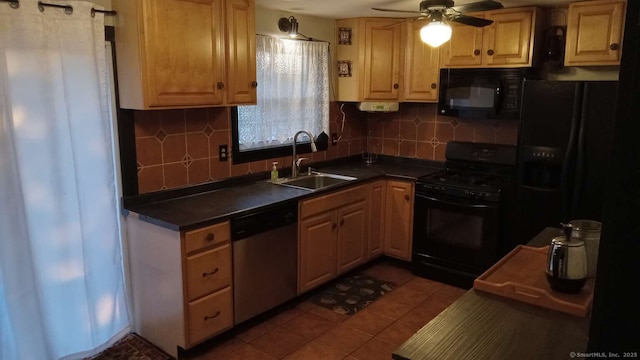 kitchen featuring dark tile patterned flooring, dark countertops, a sink, black appliances, and backsplash