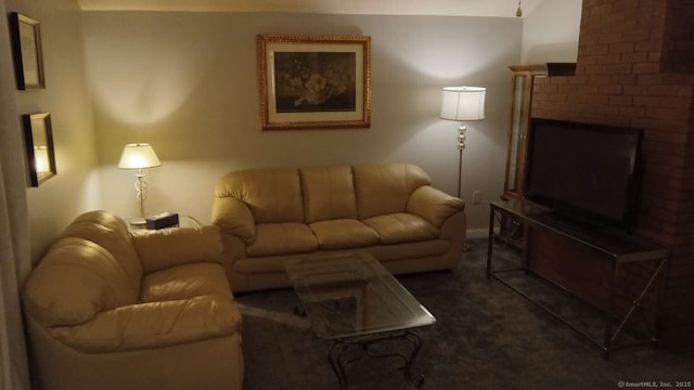 living area with dark colored carpet and a brick fireplace