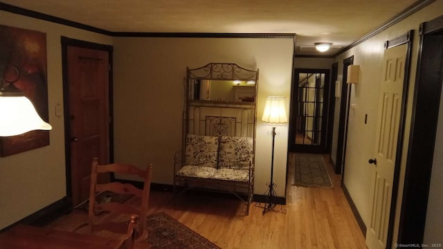 living area featuring baseboards, crown molding, and wood finished floors