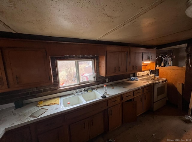 kitchen featuring brown cabinets, light countertops, a sink, and electric range