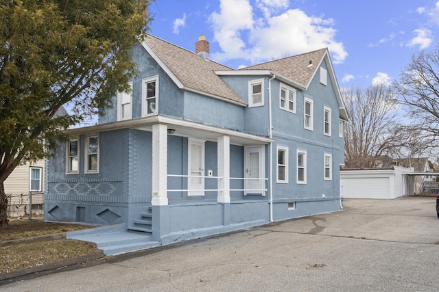 view of side of property featuring a garage, a shingled roof, a chimney, an outdoor structure, and brick siding