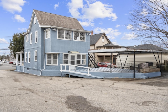 back of property featuring a shingled roof and stucco siding