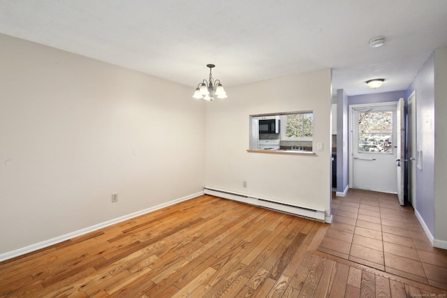 unfurnished dining area featuring a chandelier, baseboards, light wood finished floors, and a baseboard radiator