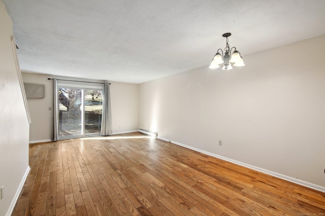 spare room featuring baseboards, wood-type flooring, and a chandelier