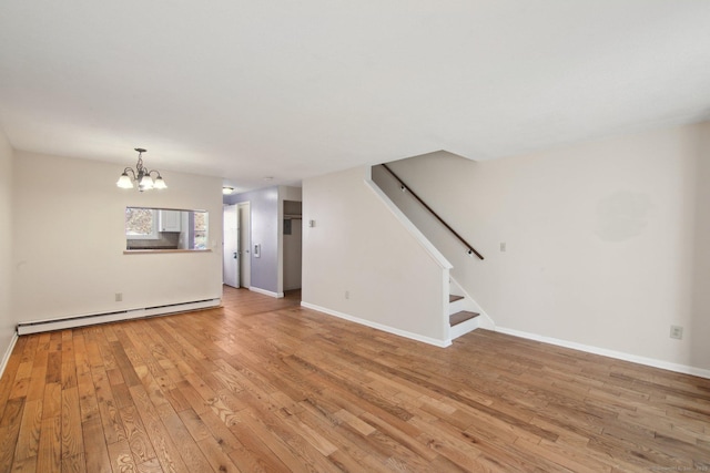 unfurnished living room with baseboard heating, stairway, light wood-type flooring, and baseboards