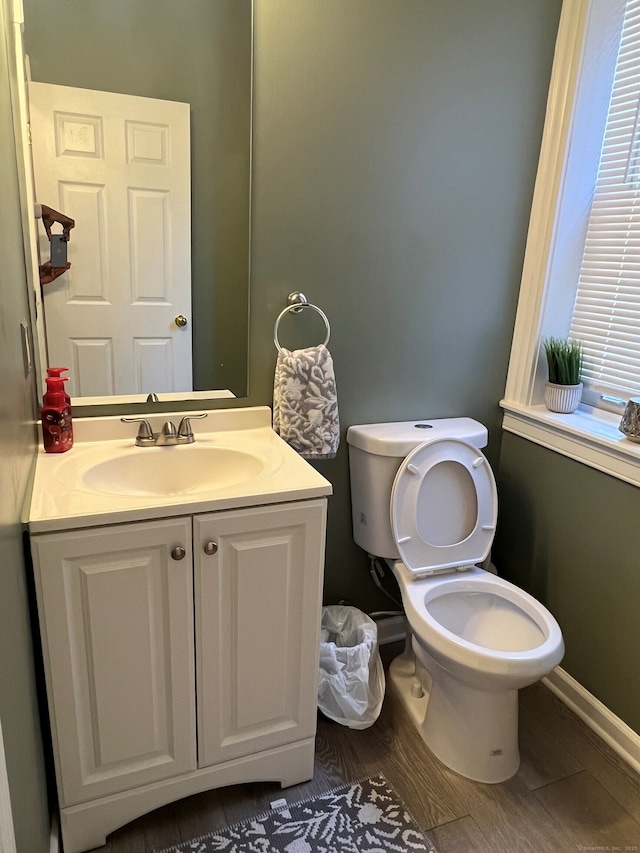 bathroom with toilet, baseboards, wood finished floors, and vanity