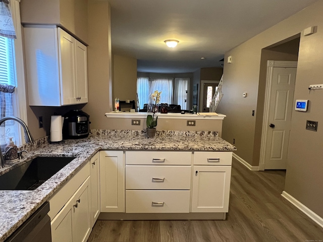 kitchen featuring white cabinets, a sink, a peninsula, and stainless steel dishwasher