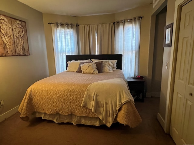 carpeted bedroom featuring multiple windows and baseboards