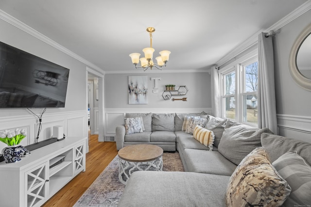 living area with a wainscoted wall, light wood-style flooring, and crown molding