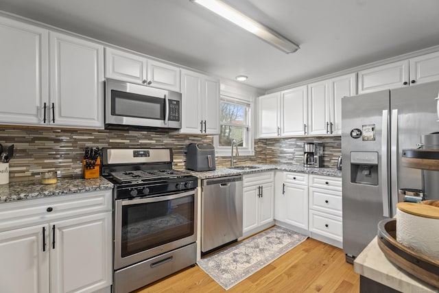 kitchen featuring white cabinets, light wood-style floors, appliances with stainless steel finishes, and a sink