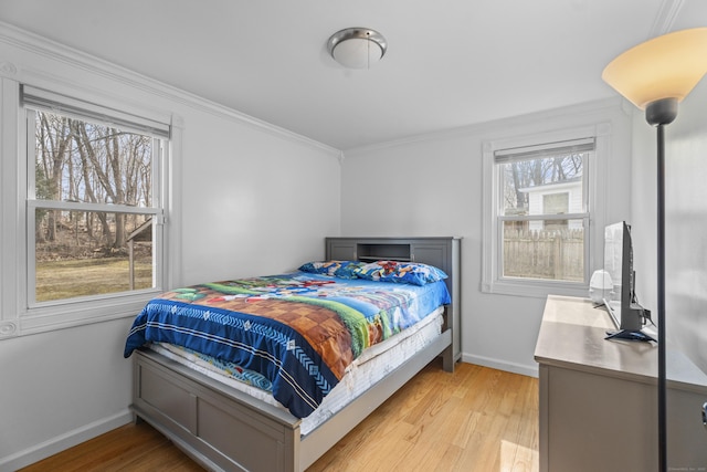 bedroom featuring light wood-style floors, baseboards, and ornamental molding