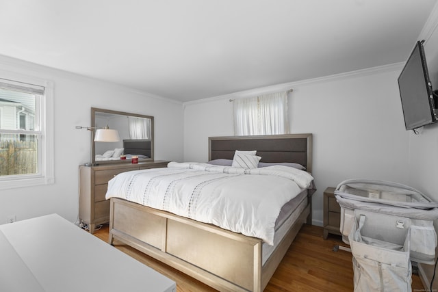 bedroom with ornamental molding and wood finished floors