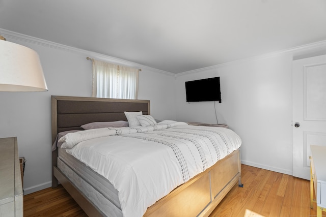 bedroom featuring crown molding, baseboards, and light wood finished floors