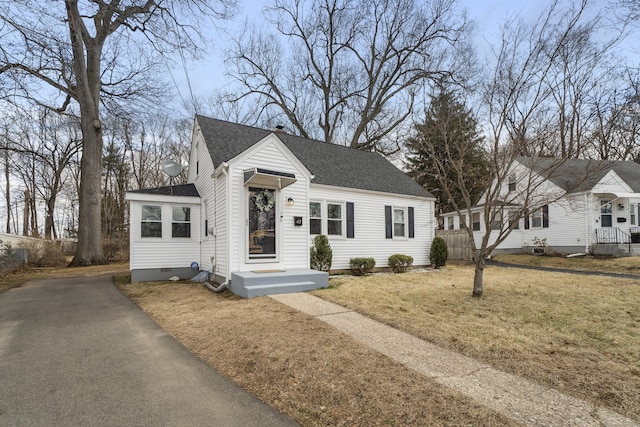 view of front of home with a front yard, fence, roof with shingles, and crawl space