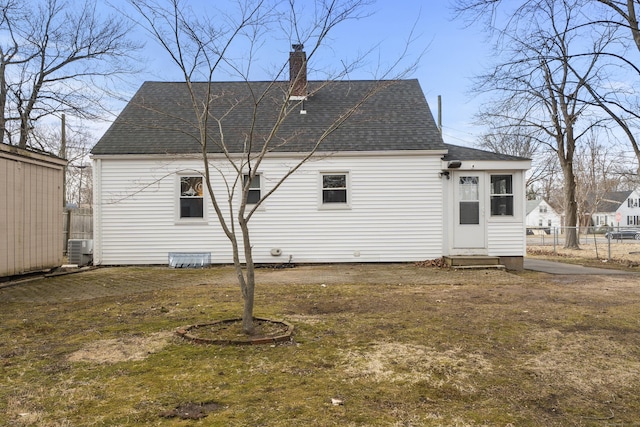 back of house with entry steps, central AC, fence, roof with shingles, and a chimney