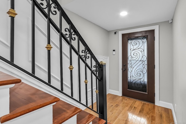 foyer featuring light wood finished floors, stairs, and baseboards