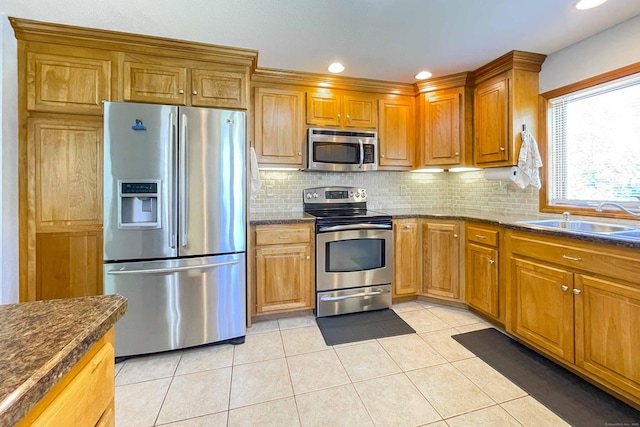 kitchen featuring a sink, stainless steel appliances, tasteful backsplash, and light tile patterned floors