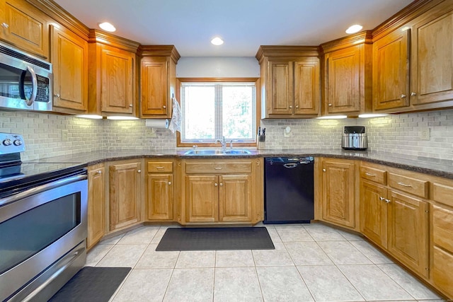 kitchen with a sink, appliances with stainless steel finishes, light tile patterned flooring, and brown cabinetry