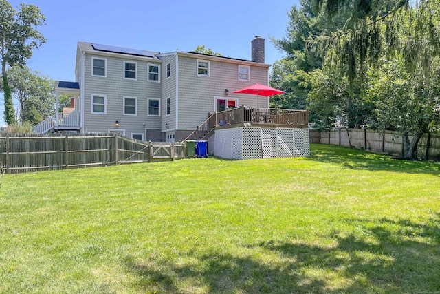 back of house featuring a deck, a yard, a fenced backyard, and a chimney