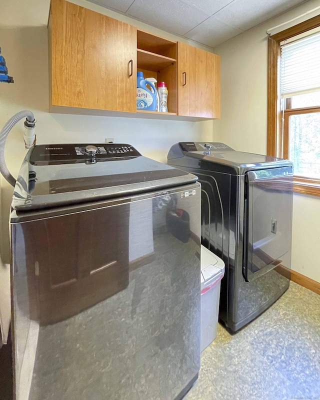 laundry area with cabinet space, independent washer and dryer, and baseboards