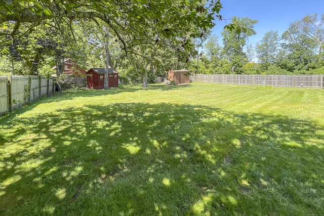 view of yard with an outbuilding, a shed, and a fenced backyard