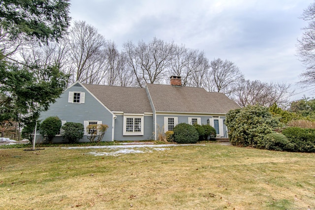 view of front of property with roof with shingles, a front lawn, and a chimney