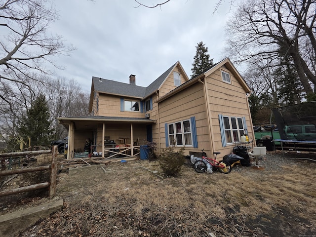 rear view of property with a trampoline, fence, and a chimney