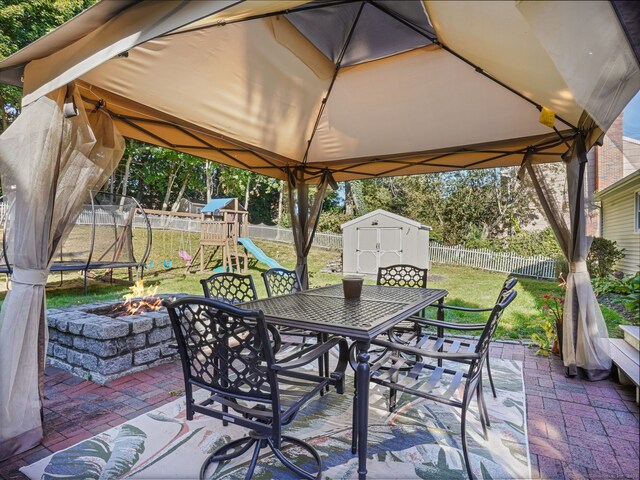 view of patio / terrace featuring a storage unit, a trampoline, a playground, and a fenced backyard