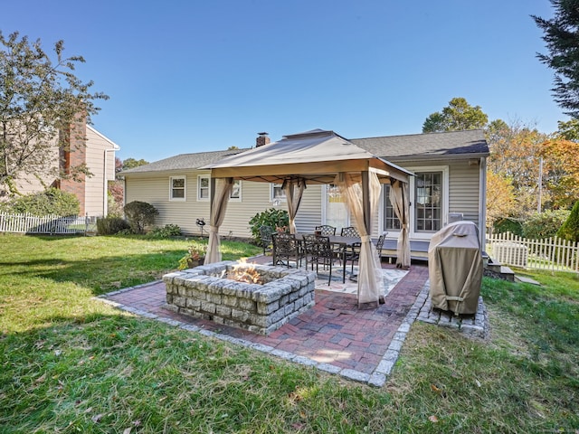 back of property with a fire pit, a patio, a gazebo, fence, and a yard