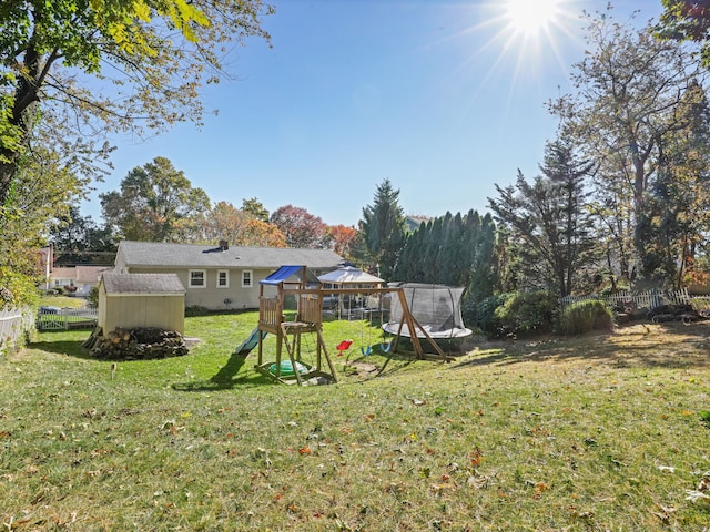 view of yard featuring an outbuilding, a playground, fence, and a storage shed