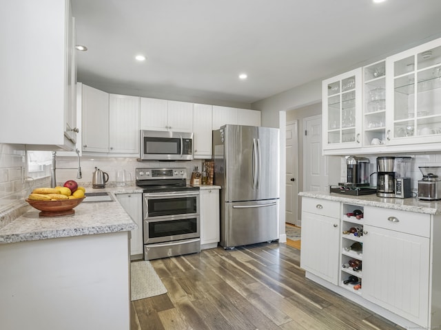 kitchen with stainless steel appliances, white cabinets, dark wood finished floors, and backsplash