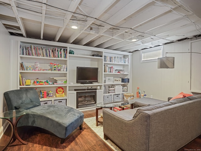 living area featuring light wood-type flooring, a glass covered fireplace, and built in features